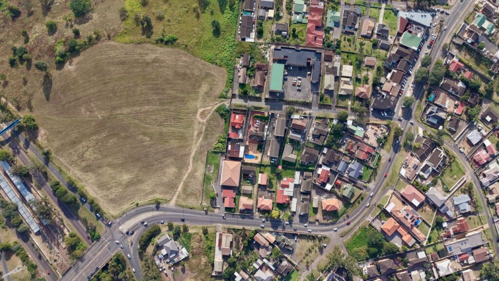 Aerial view of a suburban area in Durban, South Africa, showcasing houses and adjacent farmland.